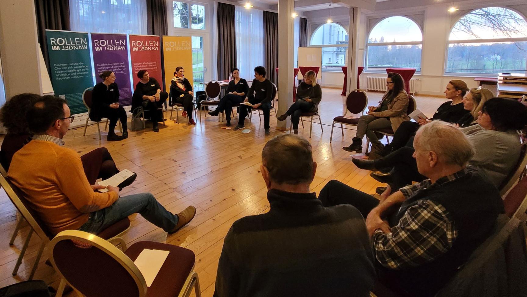 Erwachsene Menschen sitzen auf Stühlen im Kreis.