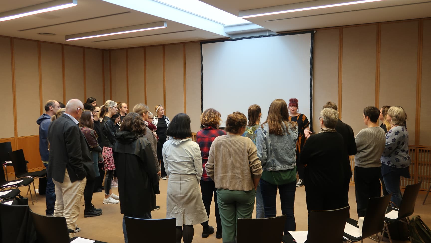 Menschen stehen im Halbkreis um die Workshopleiterin