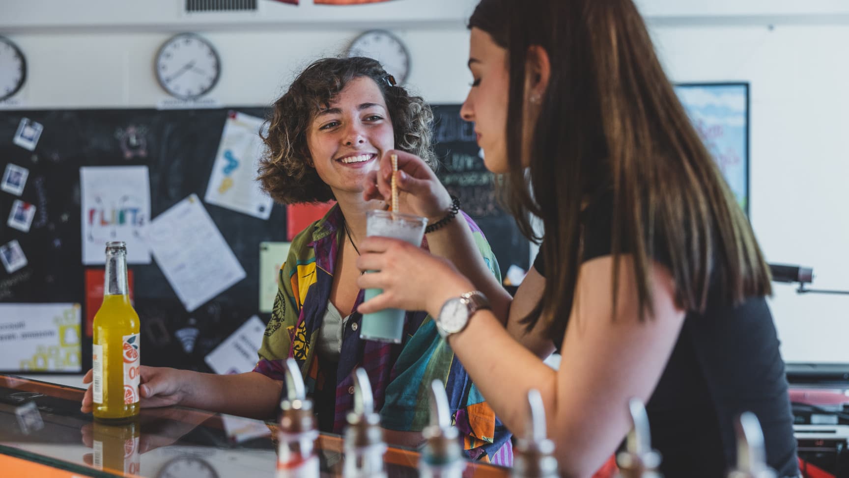 Zwei Jugendliche sitzen an einer Bar und trinken was.